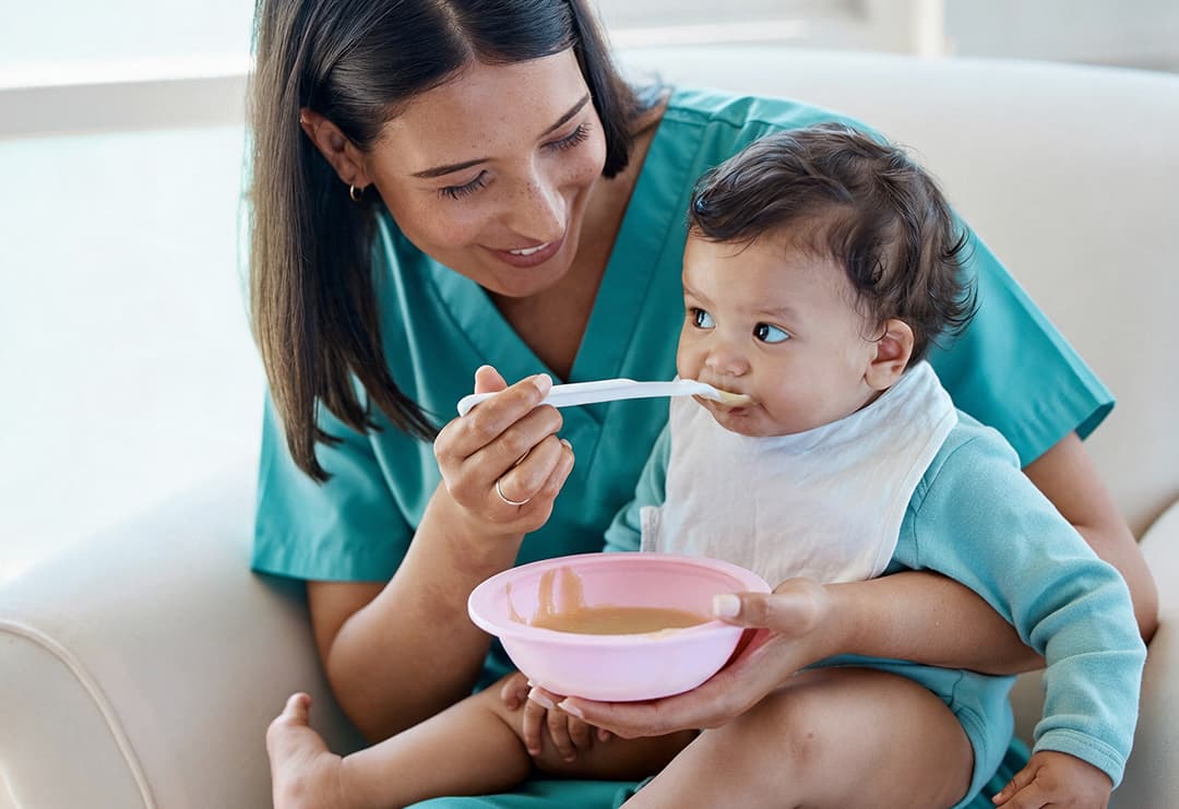 A baby sitting in a high chair with soft finger food on the tray