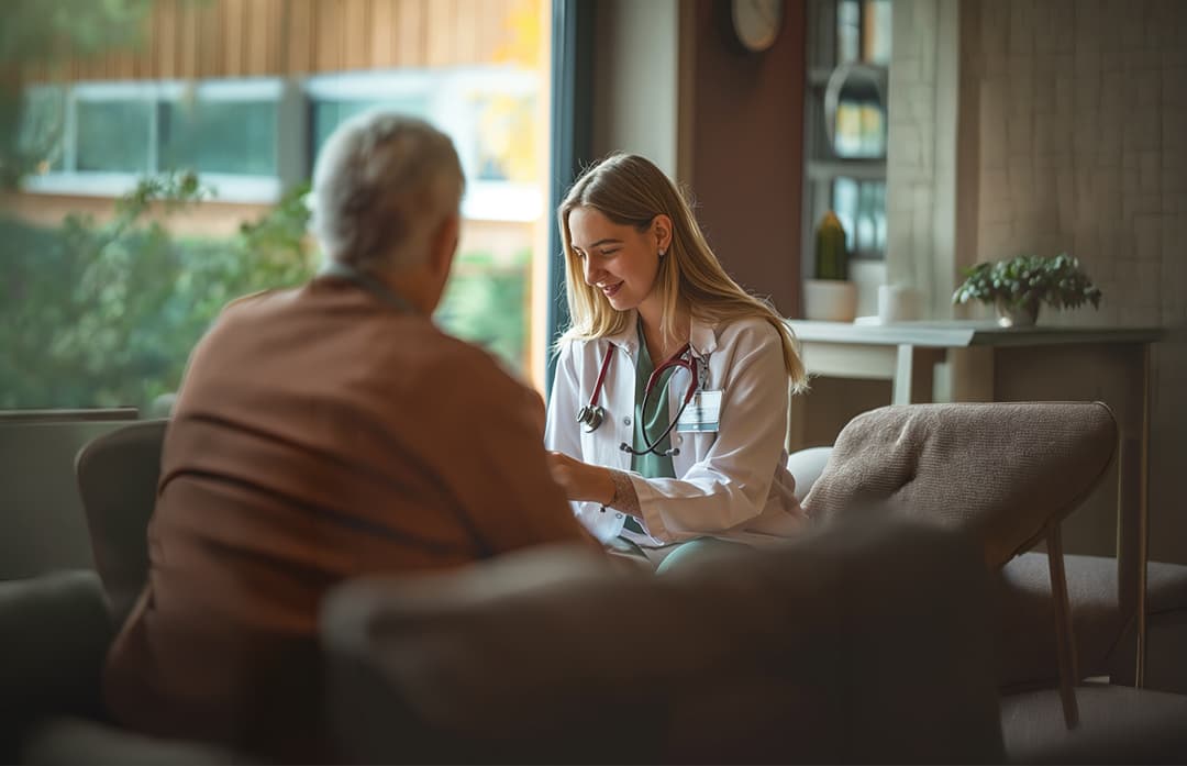 A Nightingale clinician sitting with a patient during a home visit in Dubai