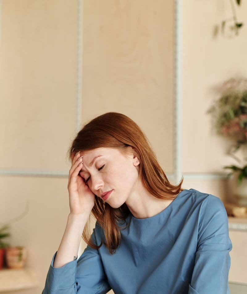 A woman at home resting her head on her hand, tired and unable to concentrate