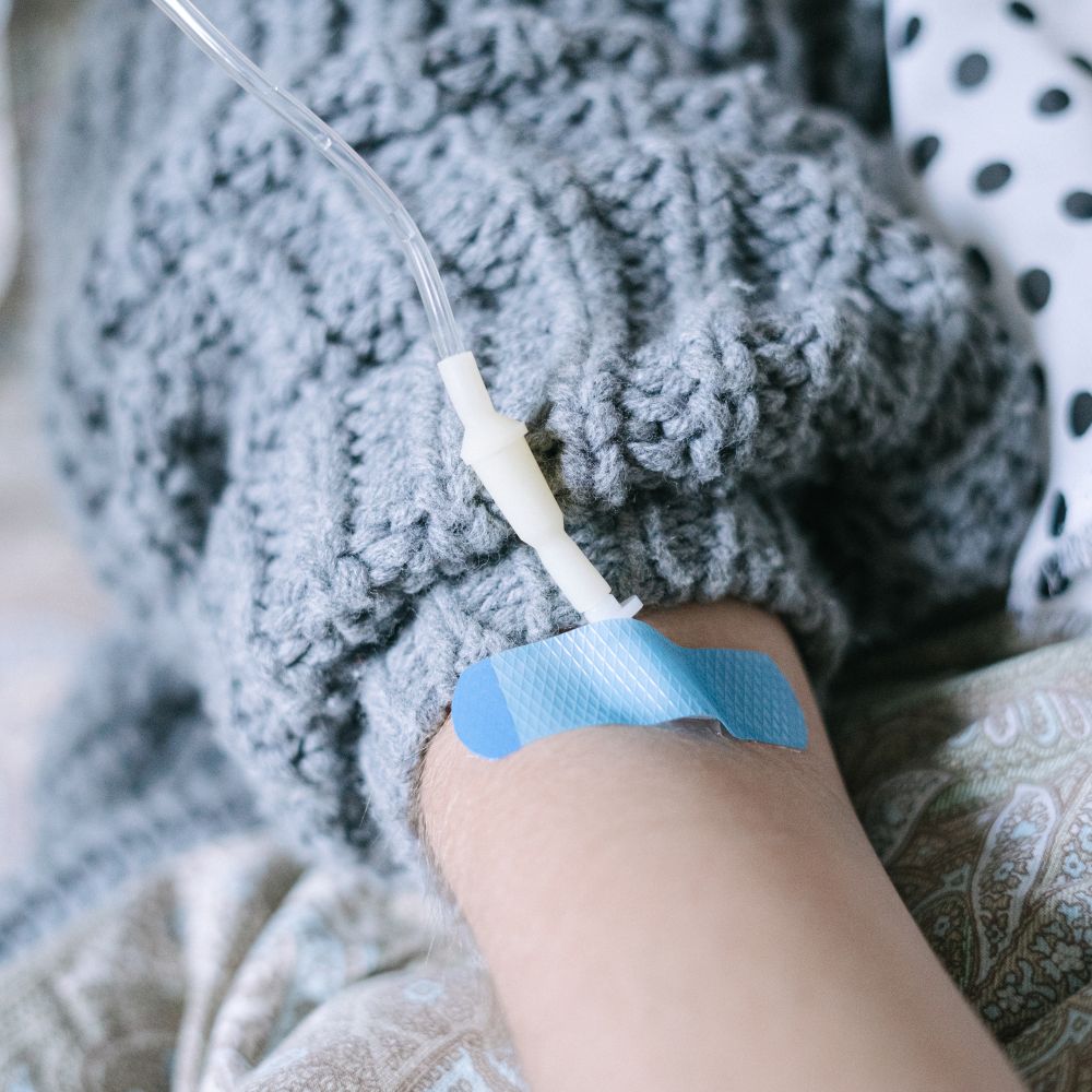 A NAD IV drip running into the hand of a patient resting at home in Dubai